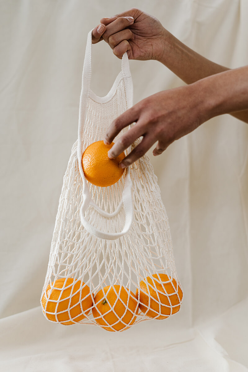 Colores y propiedades de las frutas y verduras. Bolsa de naranjas con una mano que inserta una naranja fruta de color naranja