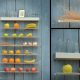 Fruitwall, los mejores fruteros modernos y de diseño para la cocina, colocado sobre pared de madera gris con ampliacion de 2 detalles. Esta lleno de frutas y verduras.